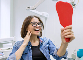  Young woman admiring her new dental implants in Clinton Township