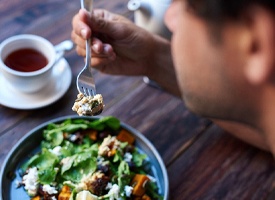 Man with dental implants in Clinton Township eating a salad