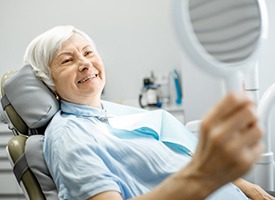 elderly woman admiring her smile in the mirror 