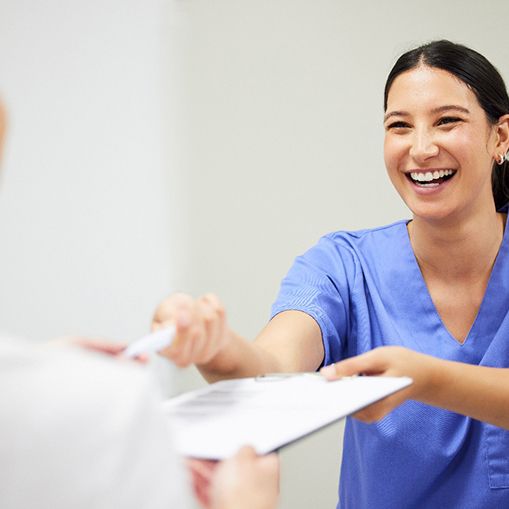 dental staff handing a patient paperwork on a clip board