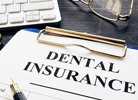 Dental insurance paperwork on desk next to glasses