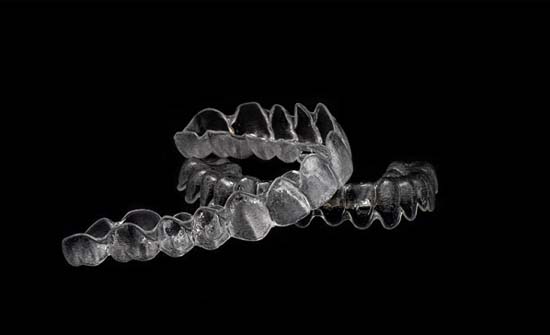 Two Invisalign® aligners in Clinton Township, MI on black background