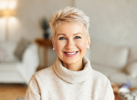 a woman in a tan sweater smiling