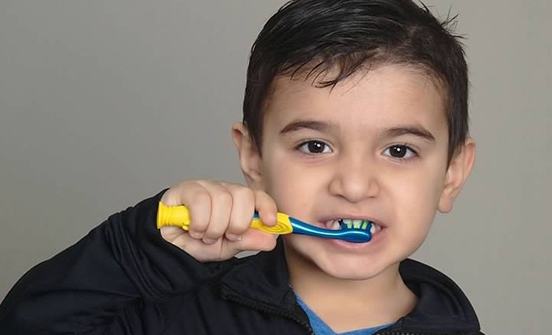 Child practicing tooth brushing with smile model