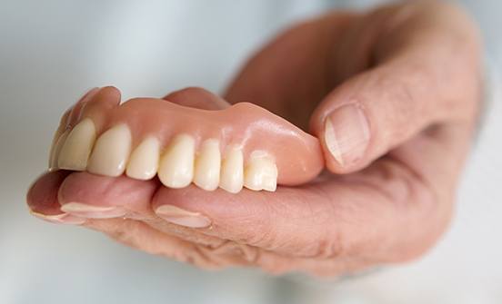 Hand holding a full denture