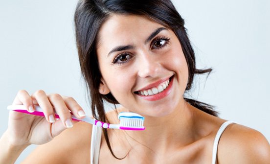 young woman holding toothbrush with toothpaste 
