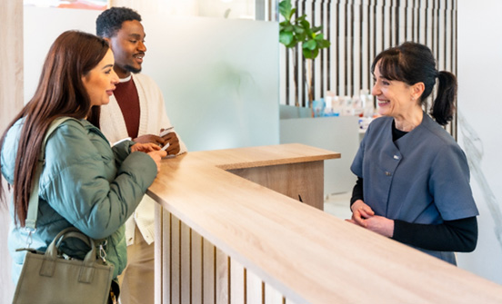 patients speaking with a front desk dental staff member