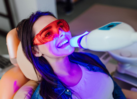 a woman having her teeth whitened at a dental office