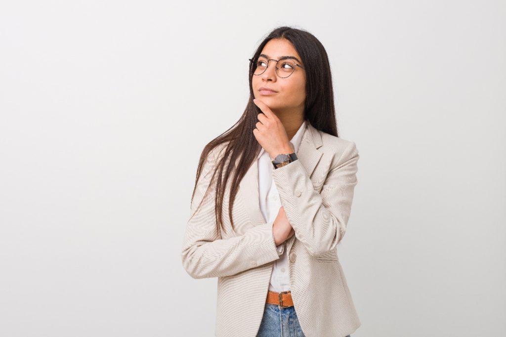 Woman with glasses thinking about teeth whitening vs veneers