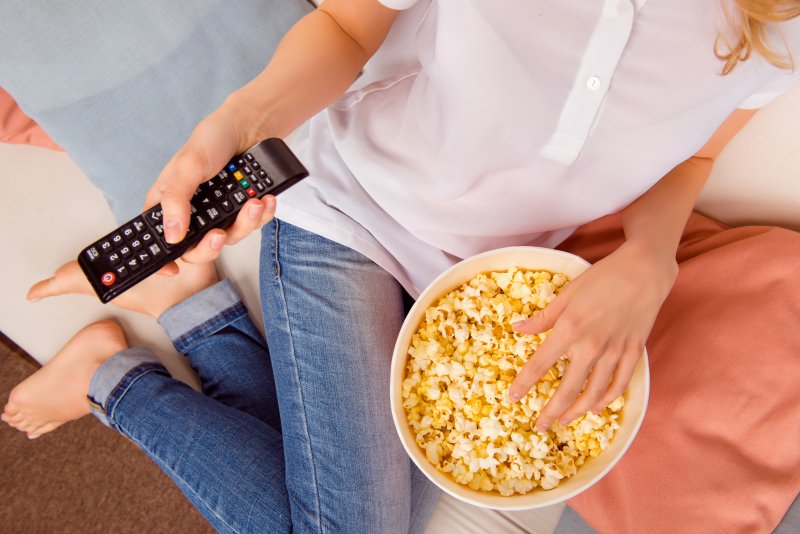 woman sitting on couch eating popcorn