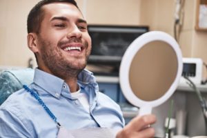 a dental patient looking in a handheld mirror