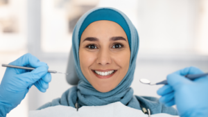 a smiling patient with a hijab on sitting in a dental chair